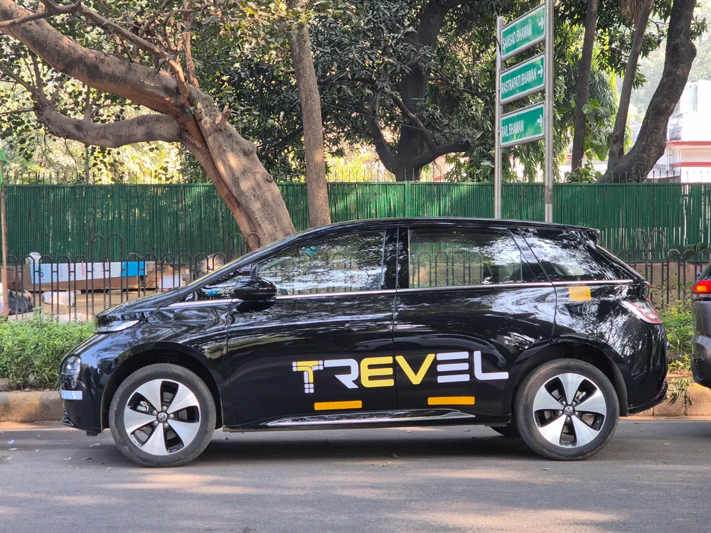 A black Trevel electric cab parked on a tree-lined city street near government buildings