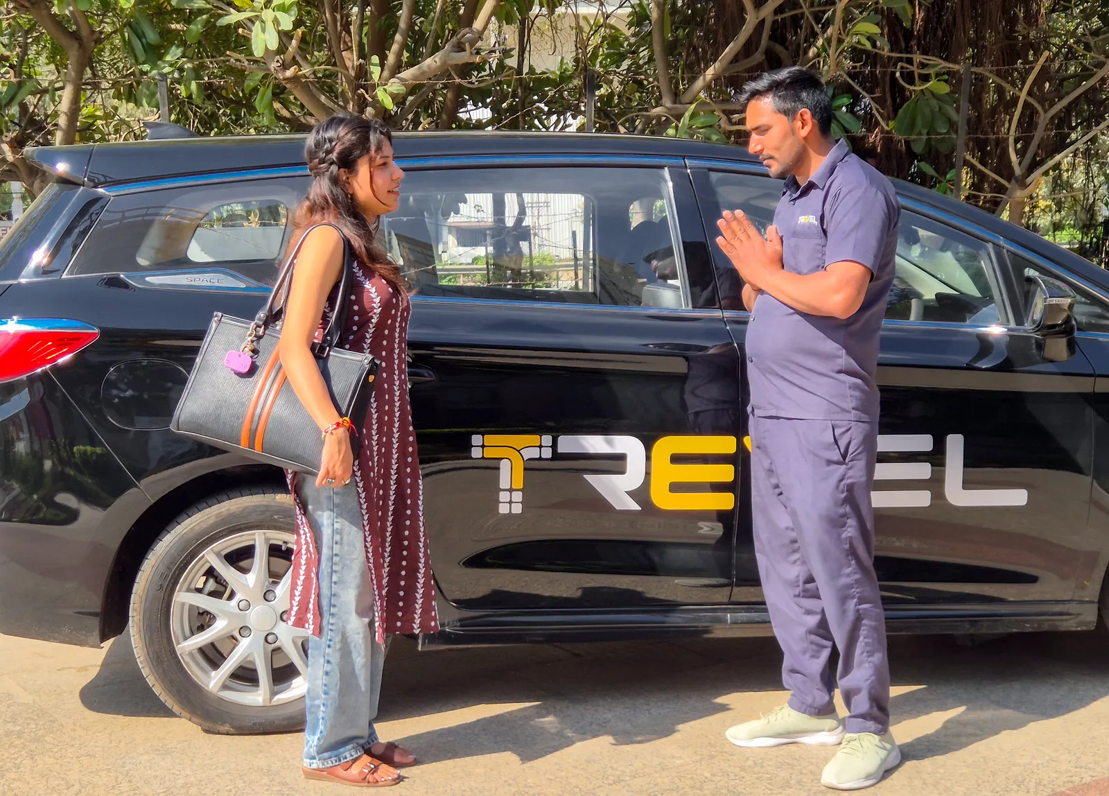 A Trevel driver greeting a passenger beside a black Trevel electric cab